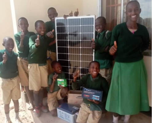 A group of children smile while presenting Ndinyika Primary School’s new solar system panel