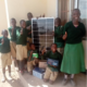 A group of children smile while presenting Ndinyika Primary School’s new solar system panel