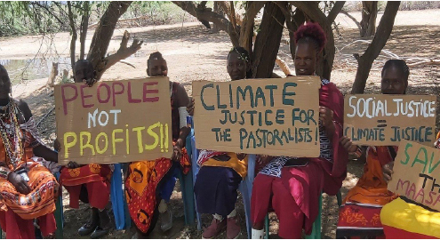 A group of people from the Masai community gather with cardboard placards protesting on climate justice.